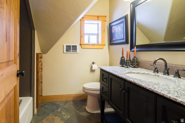 18906 North Canyon Road Whiterocks, UT 84085 - Photo 41 of 65 Full bath with vanity, a textured ceiling, dark stone finish floors, vaulted ceiling, and a tub