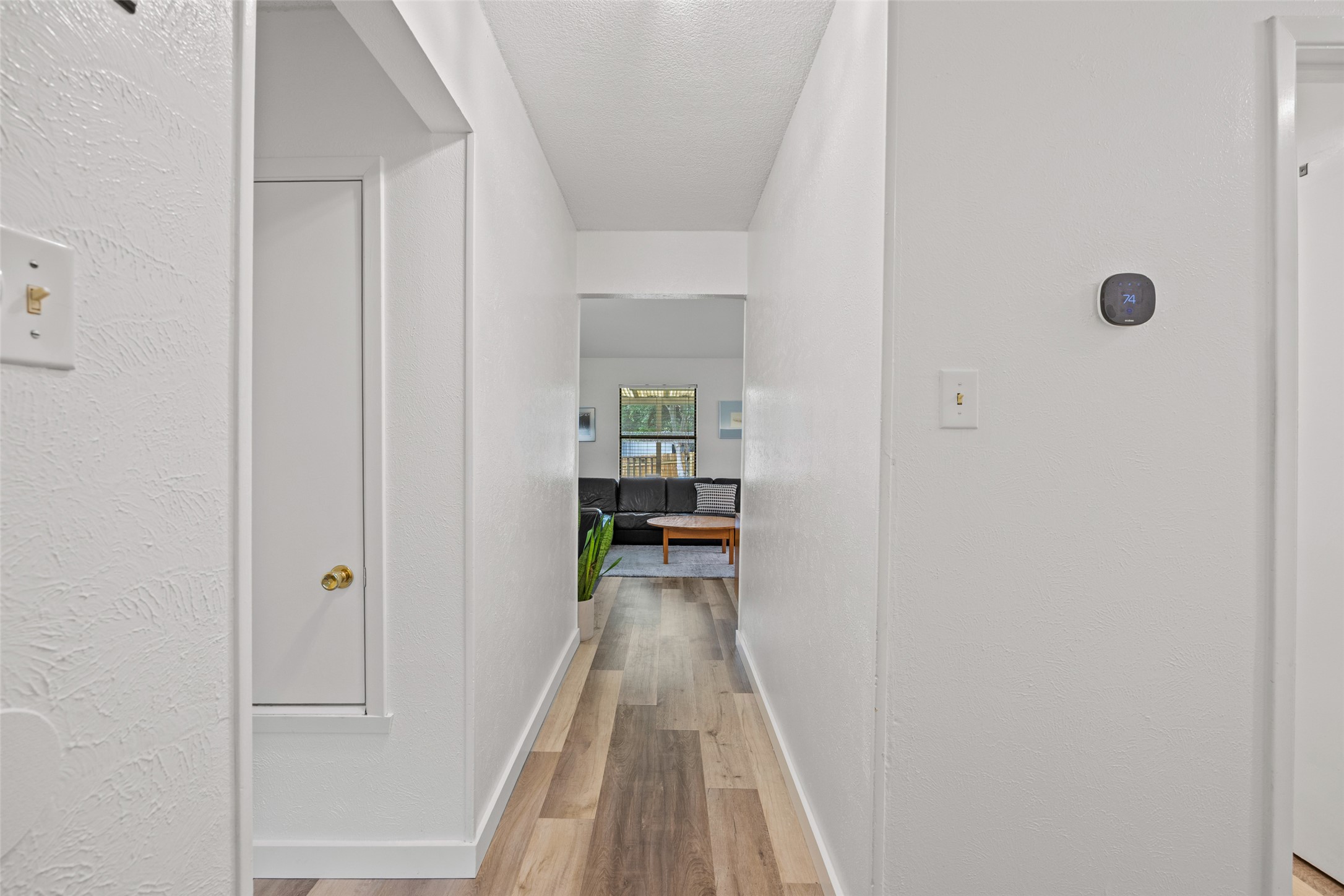 5506 South Pleasant Valley Road Austin, TX 78744 - Photo 22 of 25 A well-lit hallway with durable wood-look flooring leads to an inviting living area.