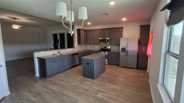 a kitchen with stainless steel appliances kitchen island granite countertop a sink stove and refrigerator