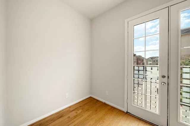 a view of an empty room with wooden floor fireplace and a window