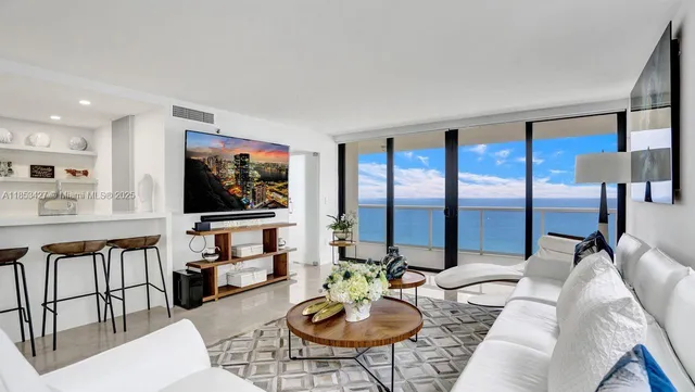 a living room with furniture a floor to ceiling window and a flat screen tv