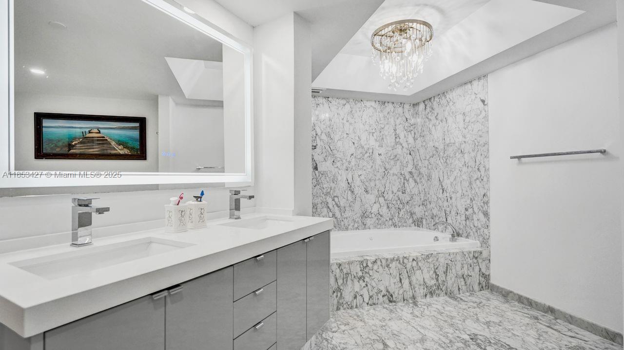 5757 Collins Avenue, Unit 1605 Miami Beach, FL 33140 - Photo 17 of 40 a bathroom with a sink a mirror and a bathtub