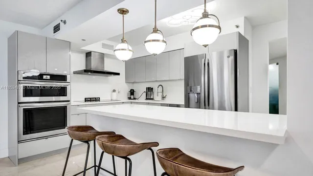 a kitchen with stainless steel appliances a stove a refrigerator and white cabinets