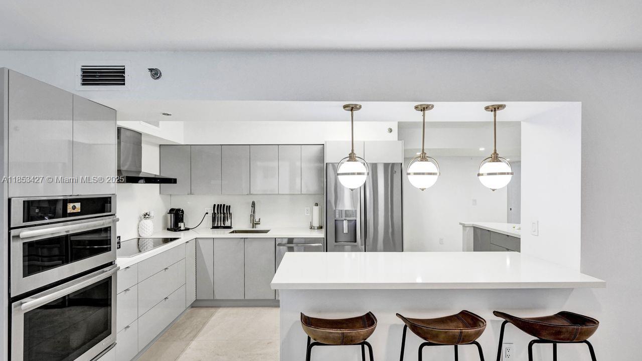 5757 Collins Avenue, Unit 1605 Miami Beach, FL 33140 - Photo 5 of 40 a large kitchen with cabinets and stainless steel appliances