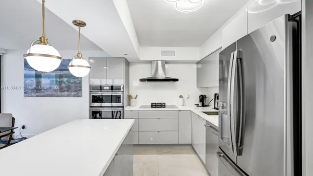 a kitchen with stainless steel appliances a refrigerator a sink a stove and white cabinets