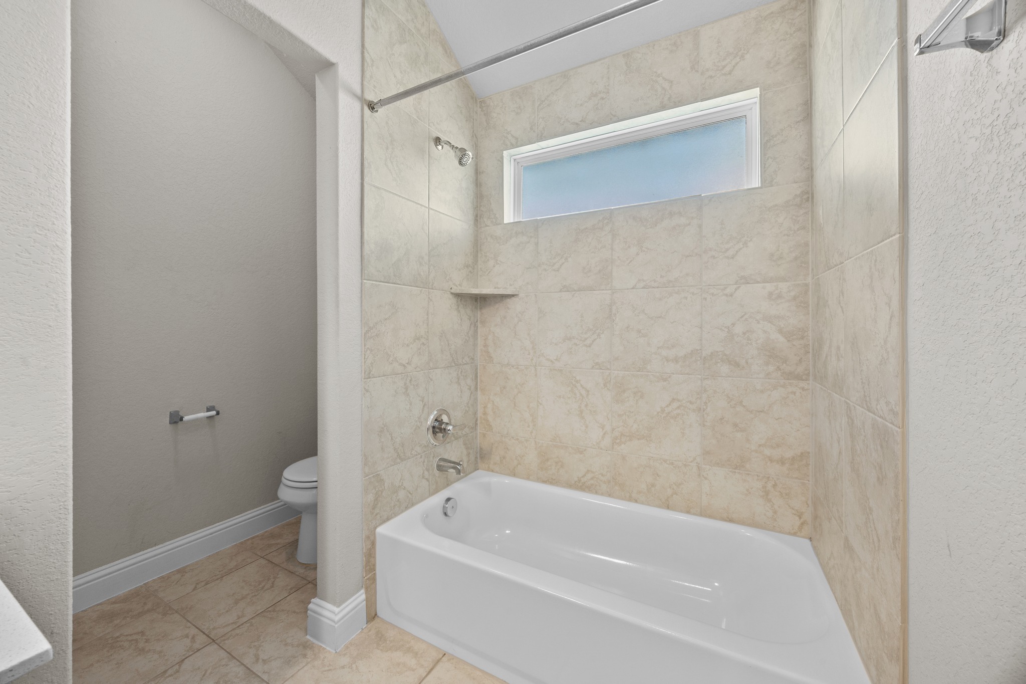 213 Graver Street Georgetown, TX 78626 - Photo 24 of 33 A well-lit bathroom features a deep tub and tiled shower, complete with an accent window.