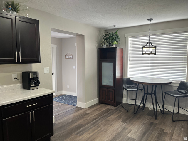 558 North N Cres Road Roosevelt, UT 84066 - Photo 27 of 31 Dark wood-finish cabinetry with silver-tone hardware, light-toned countertops, wood-finish flooring, a contemporary pendant light fixture, and a large window with blinds