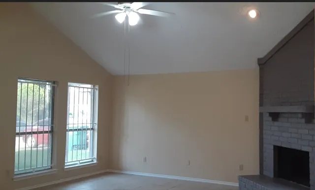 a view of an empty room with wooden floor and a fireplace