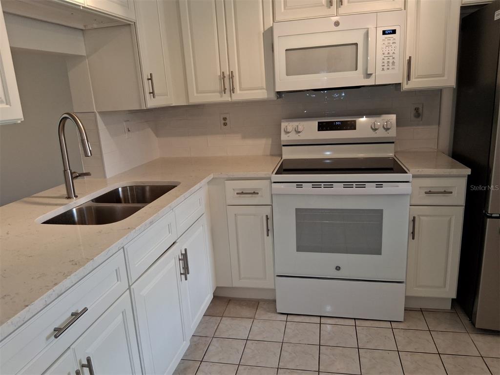 4326 Summersun Drive New Port Richey, FL 34652 - Photo 7 of 28 a kitchen with white cabinets and white appliances