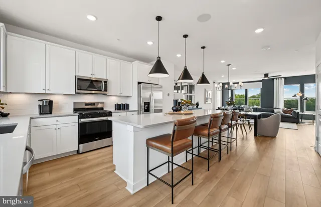 a kitchen with stainless steel appliances kitchen island granite countertop a sink a stove and a wooden floors