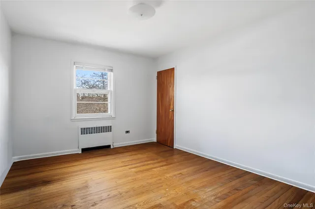 an empty room with wooden floor and window