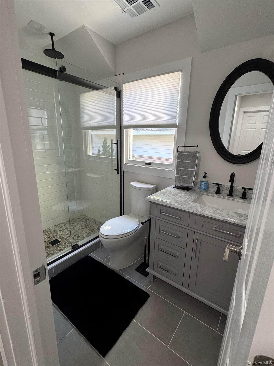 49 Canoe Place Road, Unit 312 Hampton Bays, NY 11946 - Photo 6 of 12 a bathroom with a granite countertop sink toilet a mirror and shower