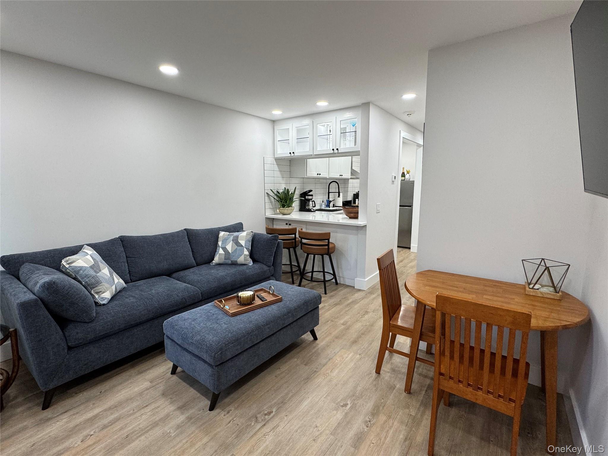 49 Canoe Place Road, Unit 312 Hampton Bays, NY 11946 - Photo 8 of 12 a living room with furniture and a dining table with wooden floor