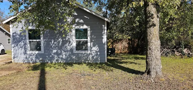 a view of a house with a yard tree and a tree