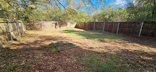 a backyard of a house with large trees and swing