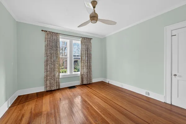 an empty room with chandelier fan and windows