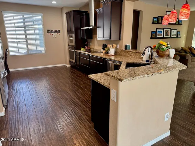 a kitchen with stainless steel appliances granite countertop a sink dishwasher stove and wooden floor