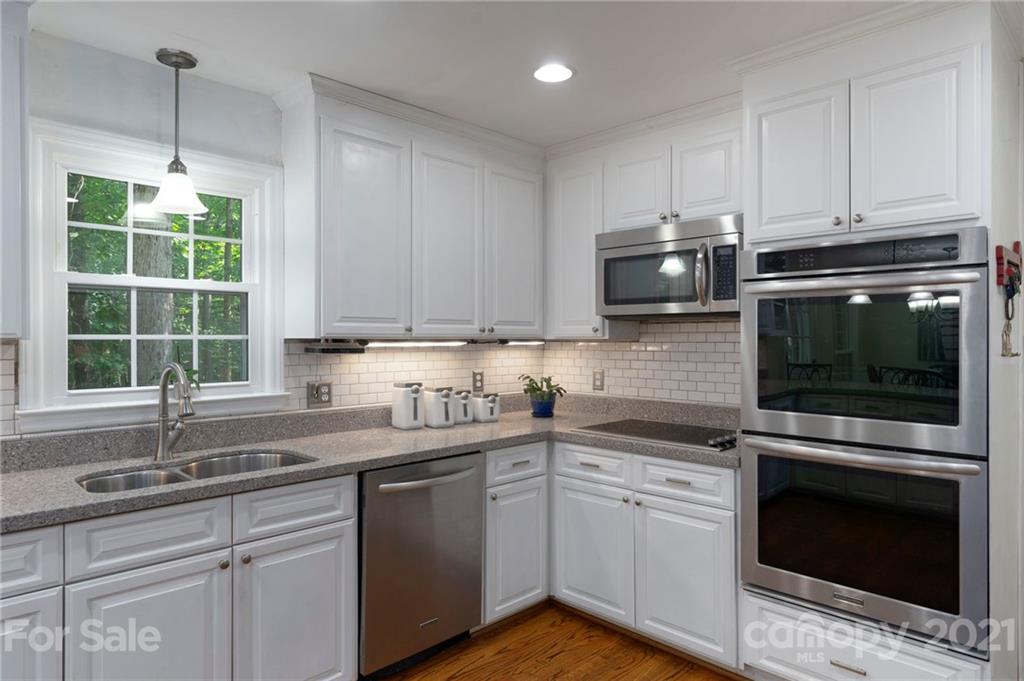 224 Raintree Drive Matthews, NC 28104 - Photo 15 of 48 a kitchen with granite countertop a stove a sink and dishwasher with wooden floor