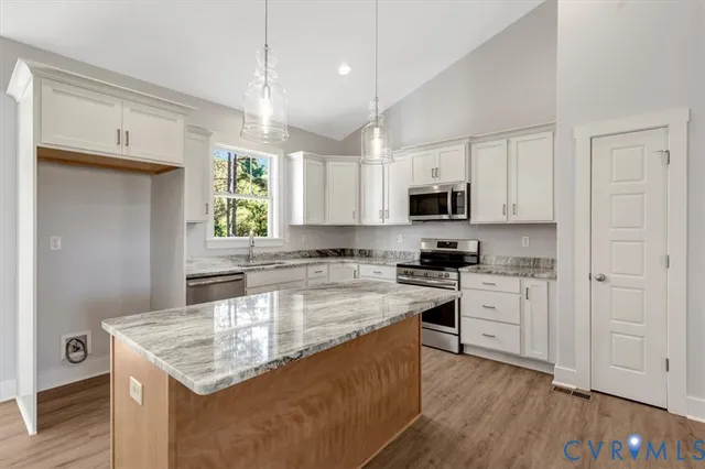 a kitchen with stainless steel appliances granite countertop a stove top oven a sink dishwasher and a refrigerator with wooden floor