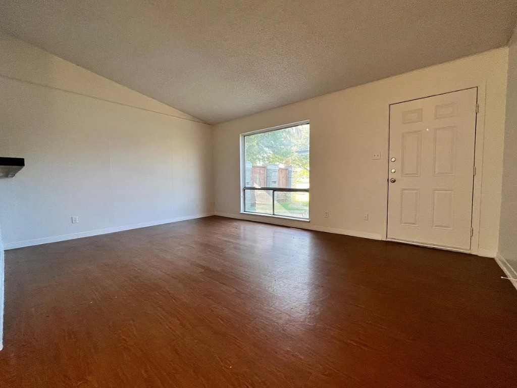 612 West 51st Street, Unit 101 Austin, TX 78751 - Photo 5 of 11 an empty room with wooden floor and windows with curtains