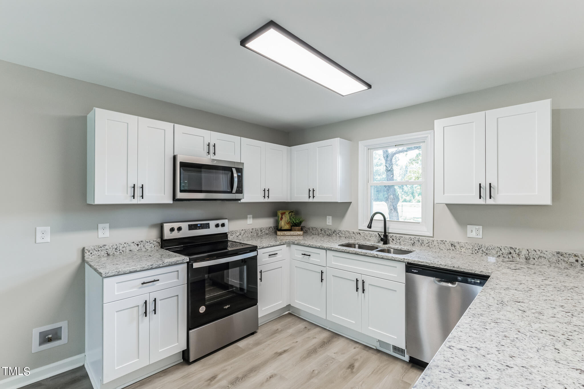 2395 Highway 210 Garland, NC 28441 - Photo 11 of 30 a kitchen with stainless steel appliances granite countertop a sink dishwasher stove and white cabinets with wooden floor