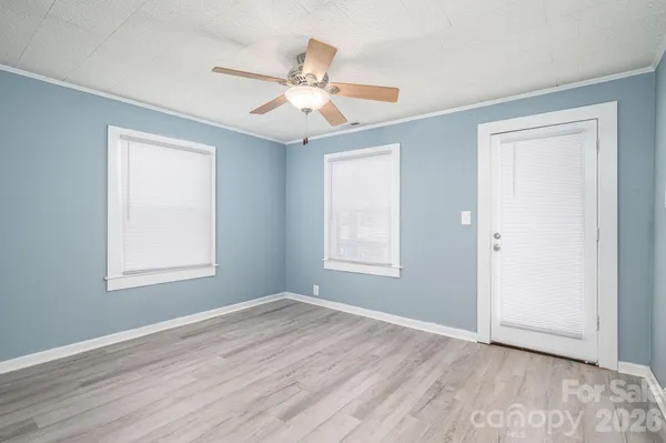 a view of an empty room with wooden floor and a window