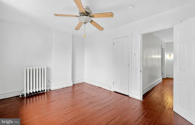 an empty room with wooden floor stairs and a chandelier fan