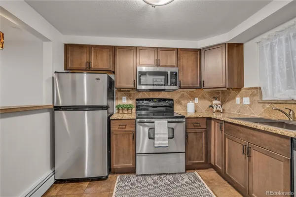 a kitchen with stainless steel appliances granite countertop a refrigerator sink and stove