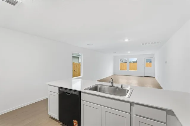 a kitchen with a sink and a stove with wooden floor
