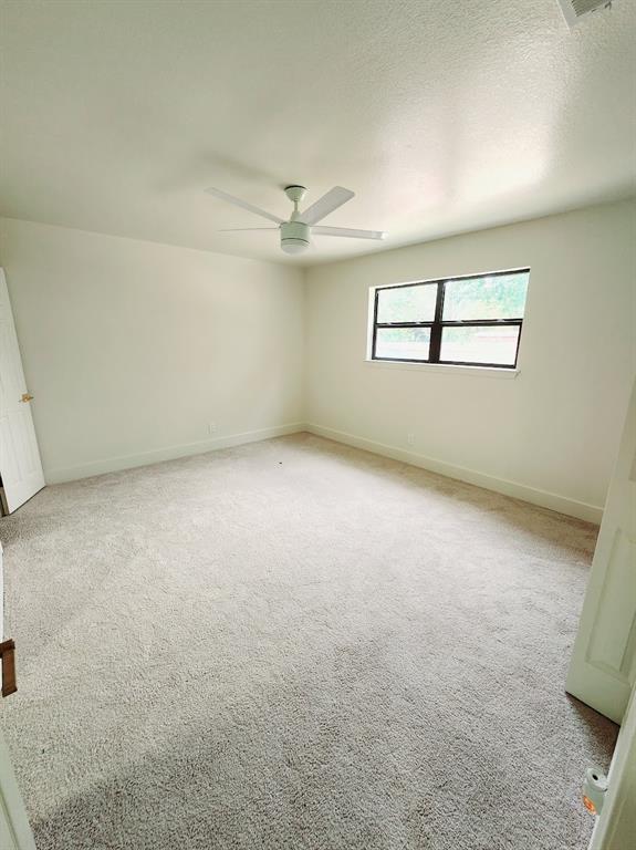 2908 Washington Street Commerce, TX 75428 - Photo 23 of 29 Neutral-toned room featuring light gray carpeting, a contemporary white ceiling fan, and a window with black trim