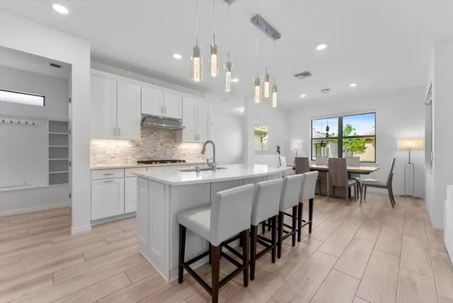 a kitchen with kitchen island granite countertop a table chairs sink and cabinets