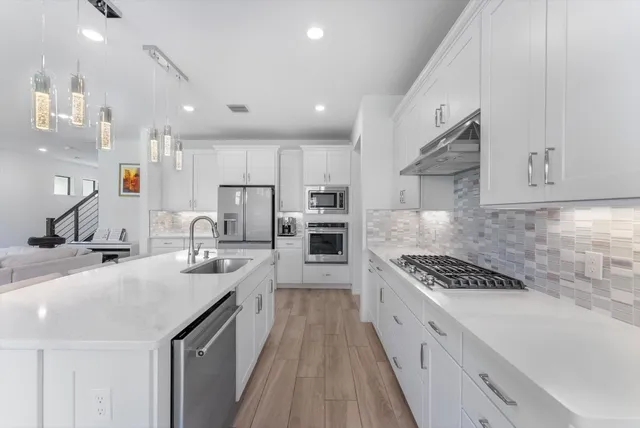 a large kitchen with stainless steel appliances granite countertop a lot of counter space and wooden floors