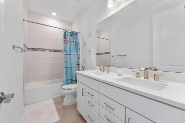 a bathroom with a double vanity sink toilet mirror and shower