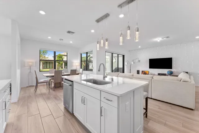 a kitchen with a sink and white cabinets with wooden floor