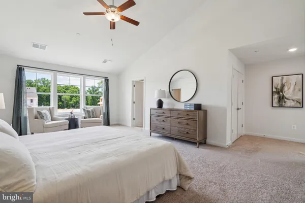 a bed room with a bed a dresser and a large window