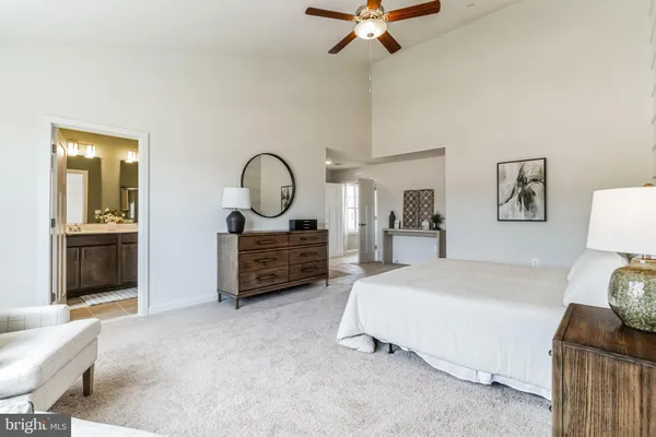 a spacious bedroom with a bed a dresser and potted plants