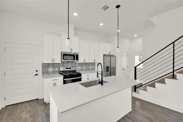 a kitchen with stainless steel appliances kitchen island wooden floors cabinets and white appliances