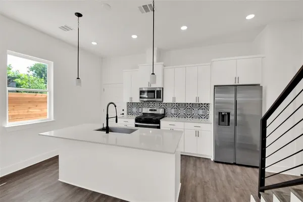 a kitchen with kitchen island a counter top space appliances and a window