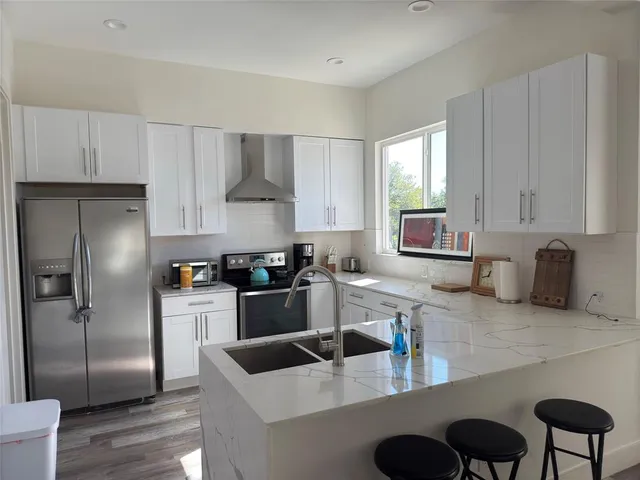 a kitchen with stainless steel appliances granite countertop a refrigerator a sink a stove and white cabinets