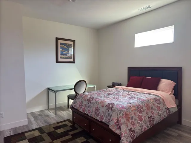 a bedroom with a bed and a dresser with wooden floor