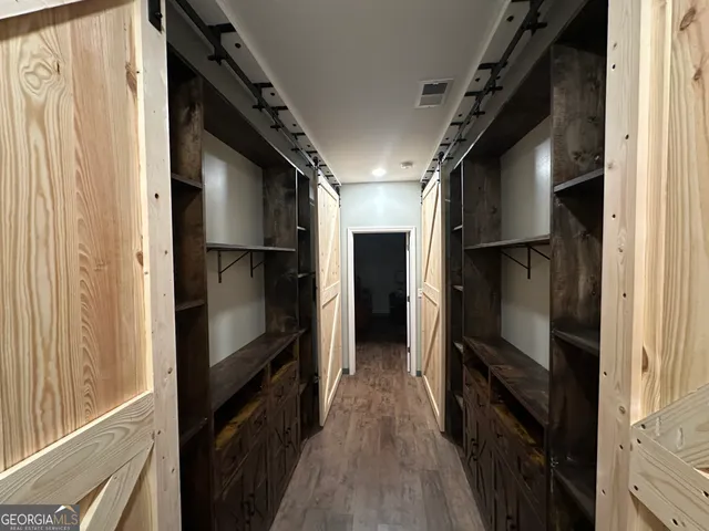 a view of hallway with wooden floor and cabinets