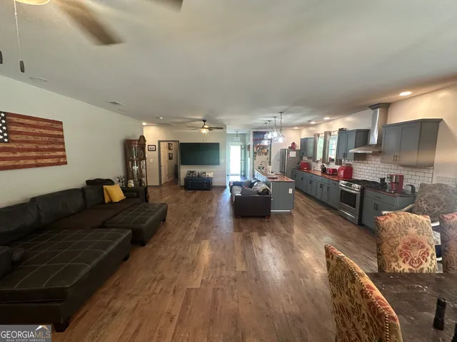 a living room with furniture kitchen area and a flat screen tv
