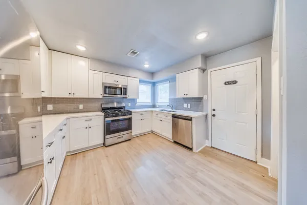 a kitchen with granite countertop white cabinets and stainless steel appliances