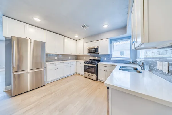 a kitchen with a refrigerator a sink and white cabinets