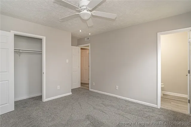 an empty room with closet and a ceiling fan