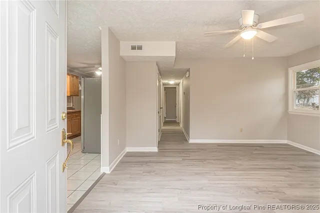 a view of a hallway with wooden floor and a chandelier fan