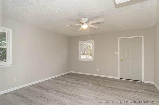 a view of empty room with wooden floor and fan