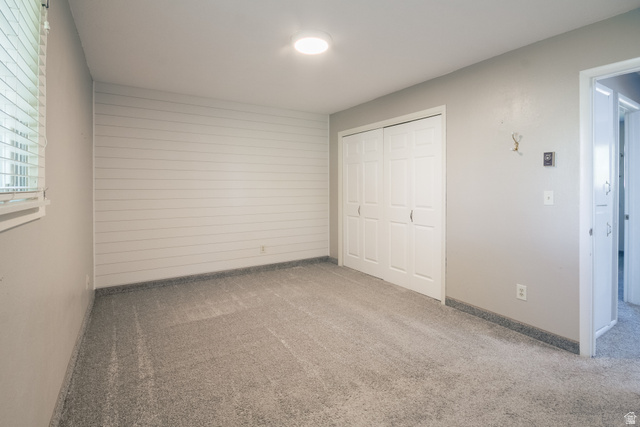 634 South 2100th Street West Vernal, UT 84078 - Photo 29 of 71 Room featuring light gray carpeting, a shiplap accent wall, white window blinds, and a double-door closet with white paneled doors