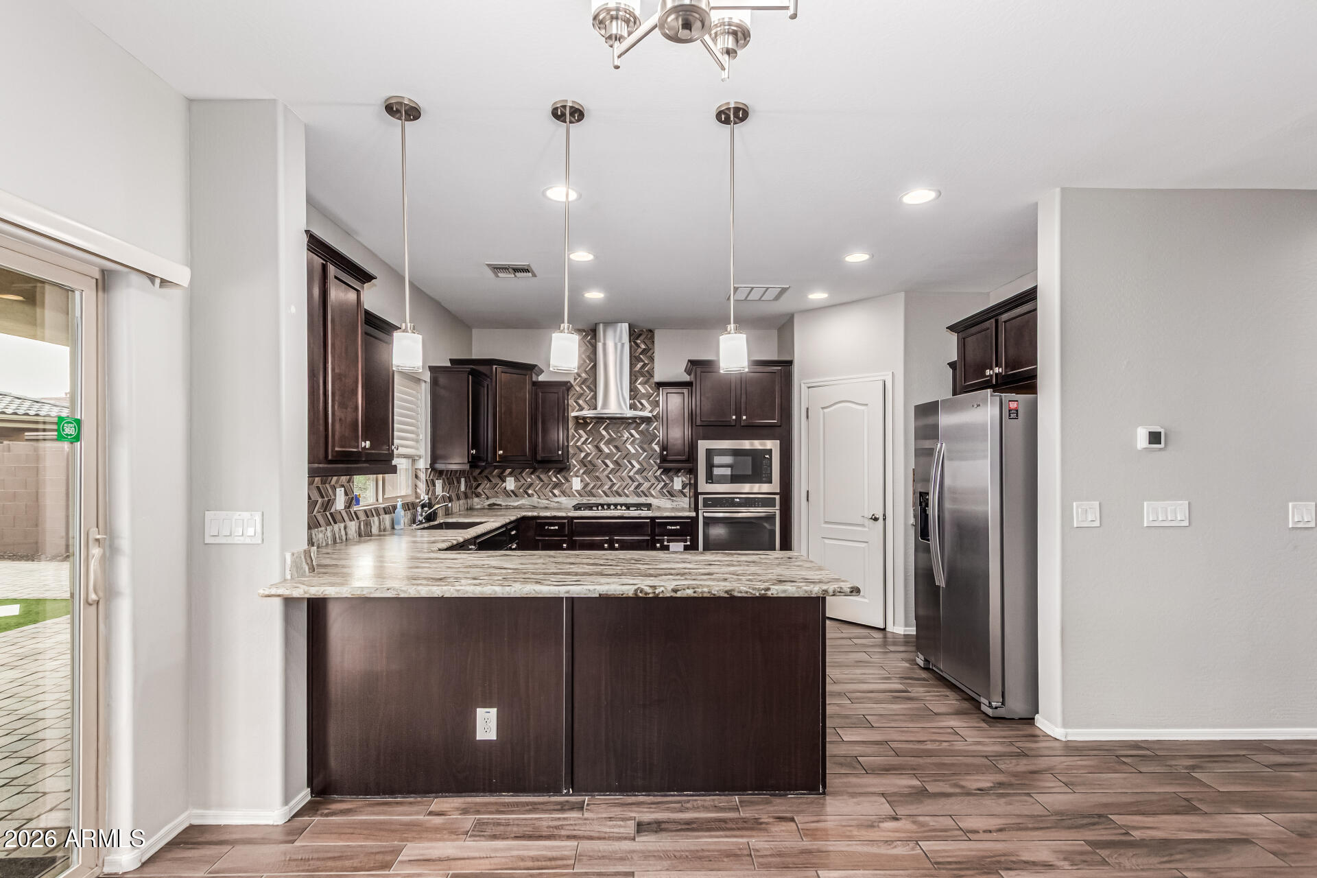 2381 East Brigadier Drive Gilbert, AZ 85298 - Photo 5 of 36 a large kitchen with stainless steel appliances kitchen island granite countertop a refrigerator a stove a sink and a oven with wooden floor