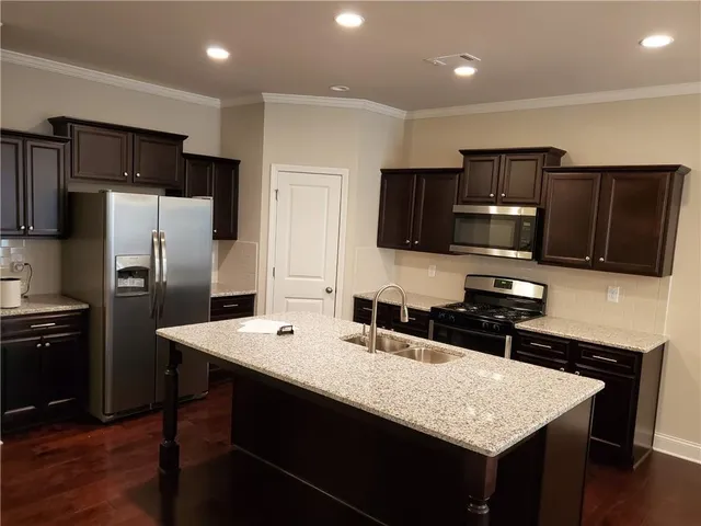a kitchen with granite countertop a refrigerator stove microwave and sink